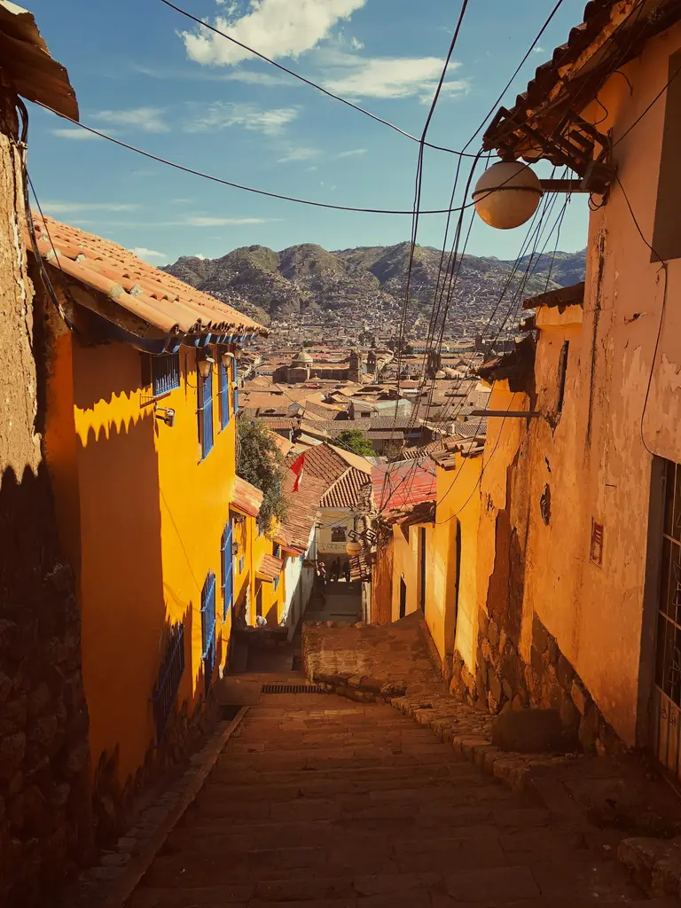Cusco'da şehir manzarası; kırmızı kiremitli çatılar, sömürge dönemi kiliseleri ve çevredeki And yamaçları.
