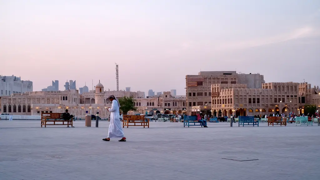 Doha'da Souq Waqif'in meydanı; kerpiç renkli alçak yapılar, ahşap kirişli cepheler ve beyaz kandurasıyla dolaşan insanlar.