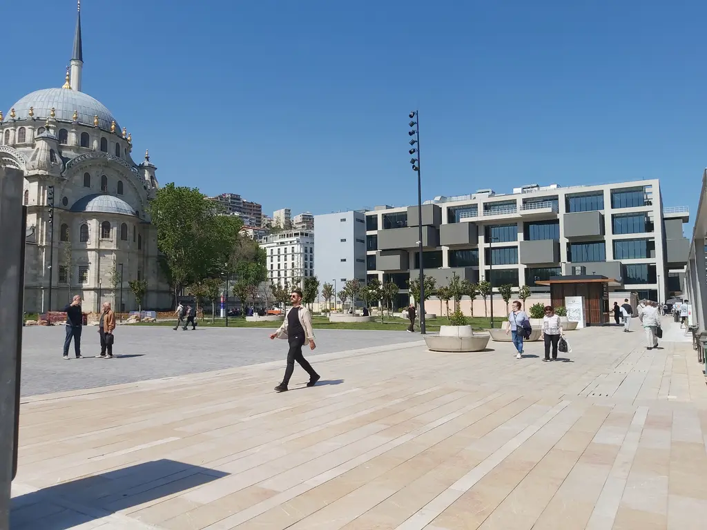 Tophane'de İstanbul Resim ve Heykel Müzesi; solda Nusretiye Camii'nin kubbesi, önde taş döşeli meydan ve yürüyen insanlar.