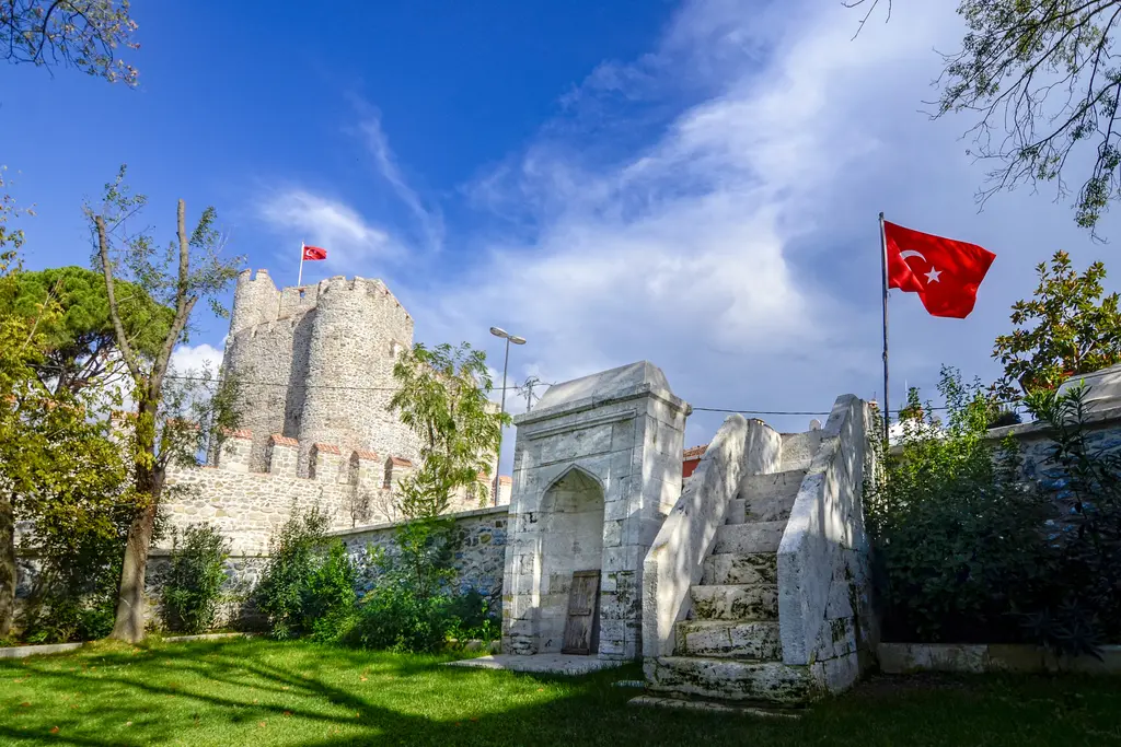 Anadolu Hisarı'nın önünde namazgah; beyaz mermer mihrap ve minber, arkada iç kale ve bayraklar.