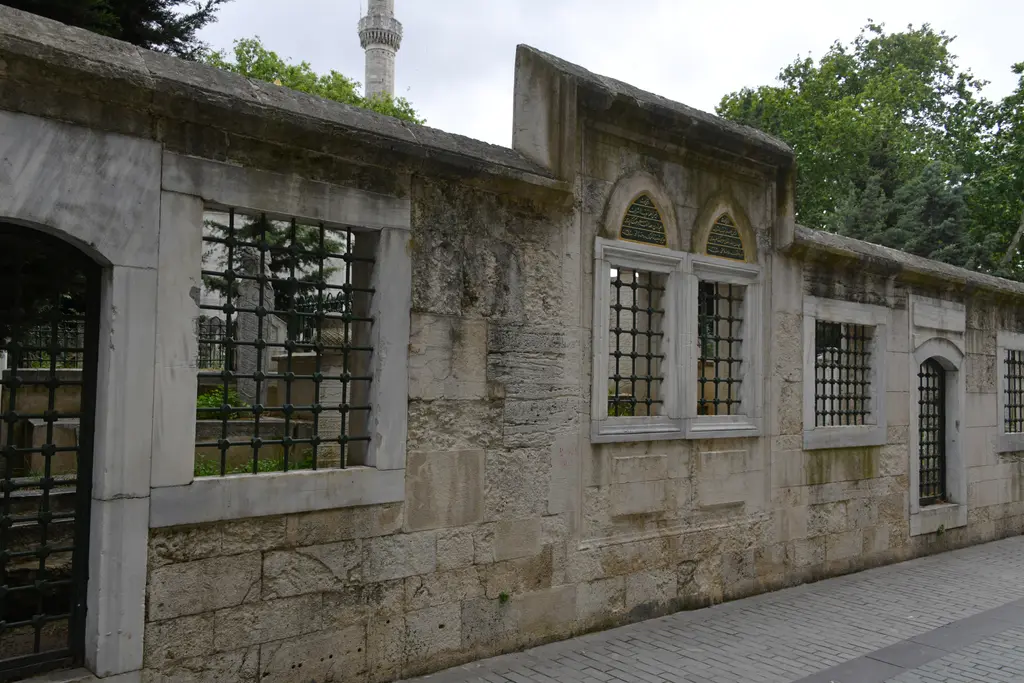 Eyüpsultan'da Balaban Yolu Sokak; demir şebekeli pencereli kesme taş hazire duvarı, kemerli kapı ve parke taşlı yol.