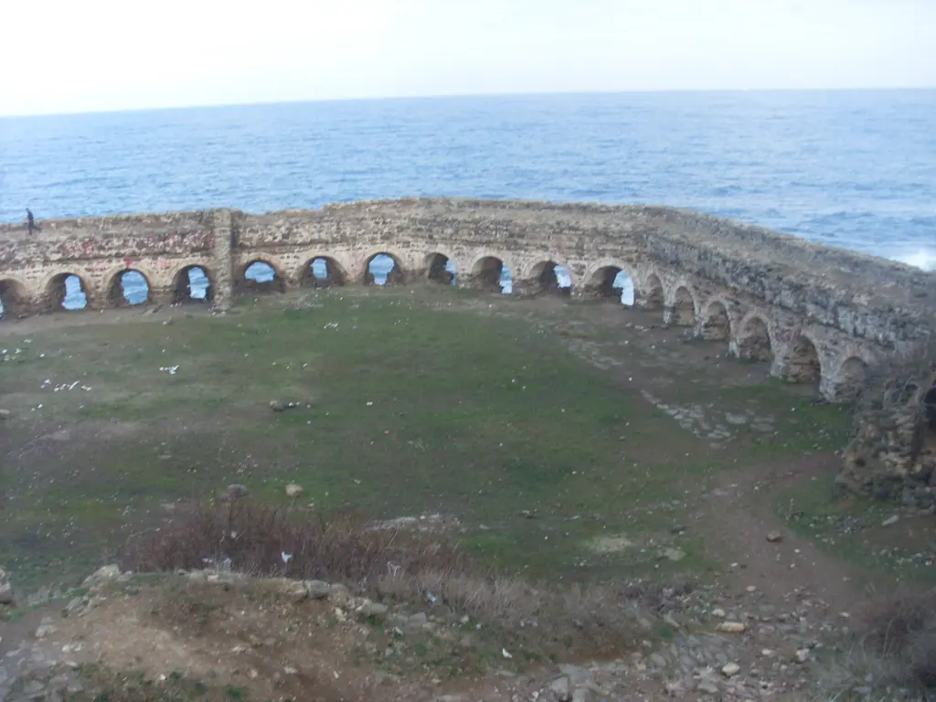 Rumeli Feneri Kalesi'nde surlar; dairesel kemerli duvar, ortada otlarla kaplı avlu ve arkada Karadeniz.