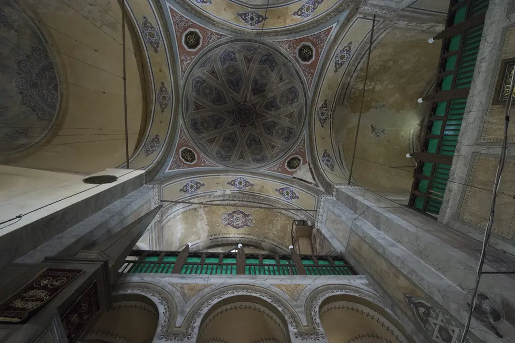 Gül Camii'nde kubbeye yukarı bakış; göbekte yıldız madalyon, pandantiflerde altı köşeli yıldızlar, altta yeşil kumaşlı ahşap galeri korkuluğu.
