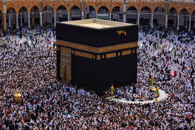 Mekke'de Mescid-i Haram'ın avlusundaki Kâbe; siyah örtüsü, çevresini halka halka saran kalabalık ve arkada avluyu kuşatan kemerli revaklar.
