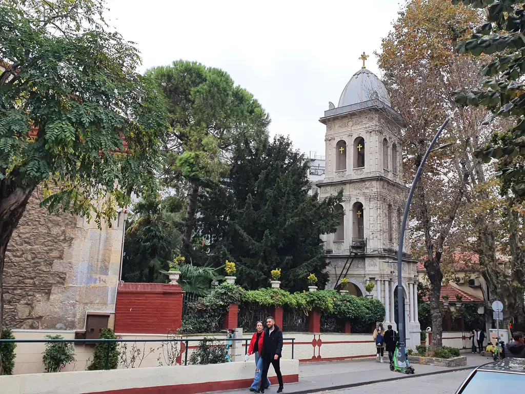 Kuzguncuk'ta Aya Pantelimon Rum Kilisesi; kemerli pencereli taş gövde, kiremit çatı ve yanında beyaz çan kulesi.