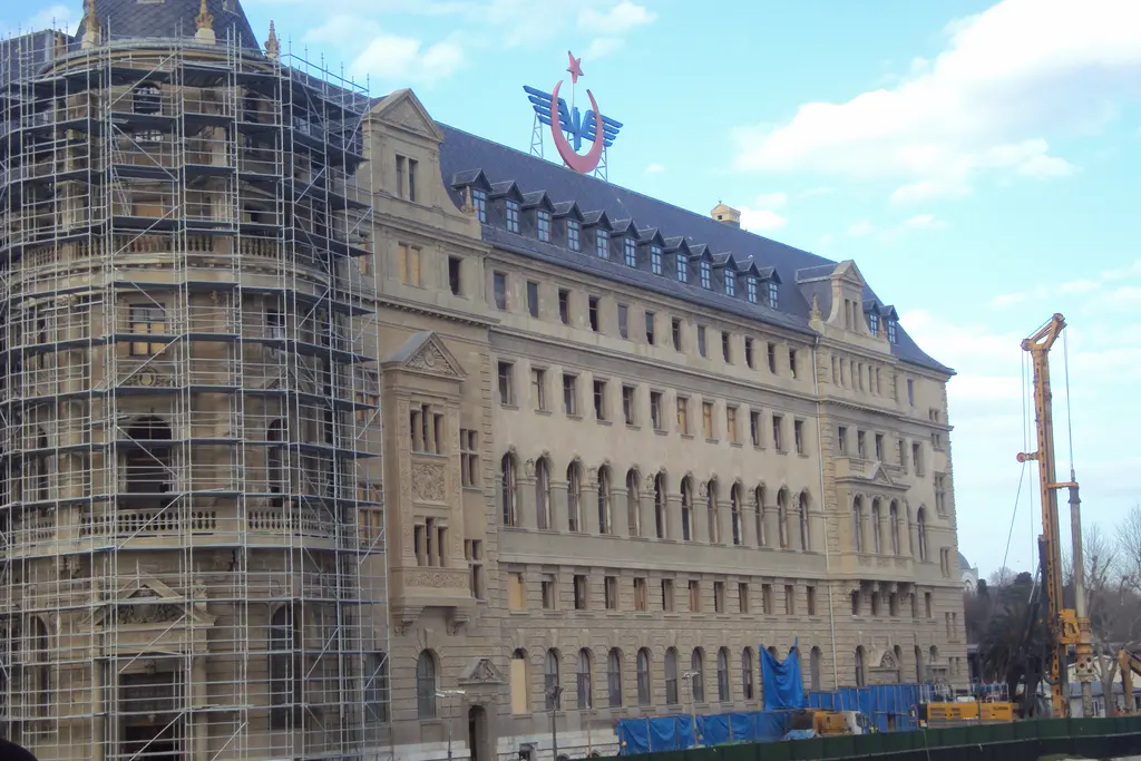 Haydarpaşa Garı; iskelelerle sarılmış taş cephe, sivri külahlı kuleler, kırmızı çatı ve önünde vinç.