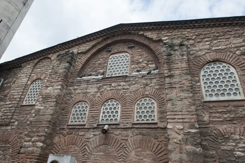 Atik Mustafa Paşa Camii'nin yan duvarı; büyük tuğla kemerin içinde şebekeli pencere, altında üç küçük kemerli pencere dizisi ve duvar boyunca yelpaze gibi açılan tuğla kemerler.