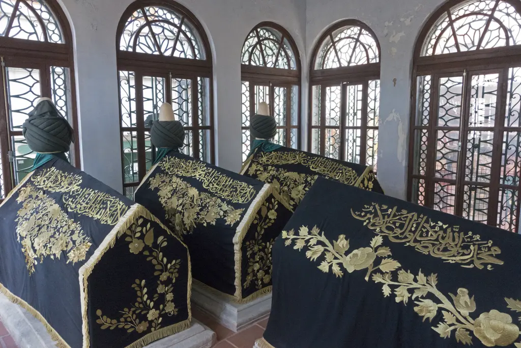 Halet Efendi Türbesi'nin içinde işlemeli siyah örtülü sandukalar; arkada kemerli, parmaklıklı büyük pencereler.