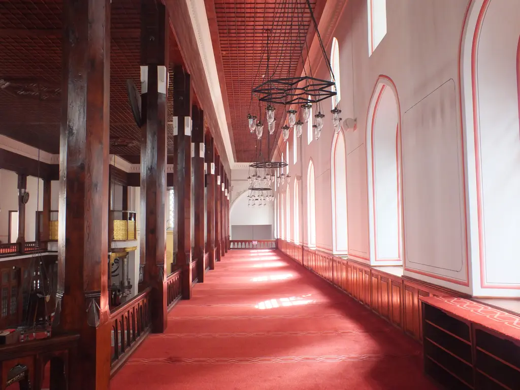 Arap Camii'nde mahfil katı; kırmızı halılı uzun galeri, ahşap korkuluk, sivri kemerli pencereler ve beyaz duvarlar.
