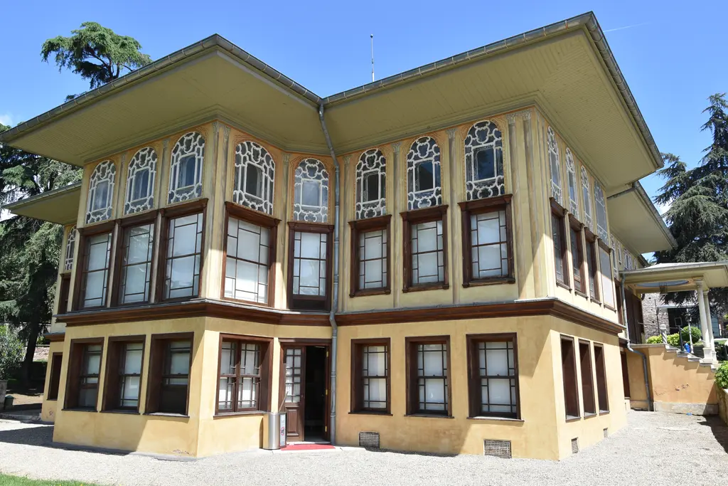 Aynalıkavak Kasrı'nın köşesi; iki cephe boyunca dizilen dikdörtgen ve kemerli pencereler, sarı duvarlar ve geniş saçaklı çatı.