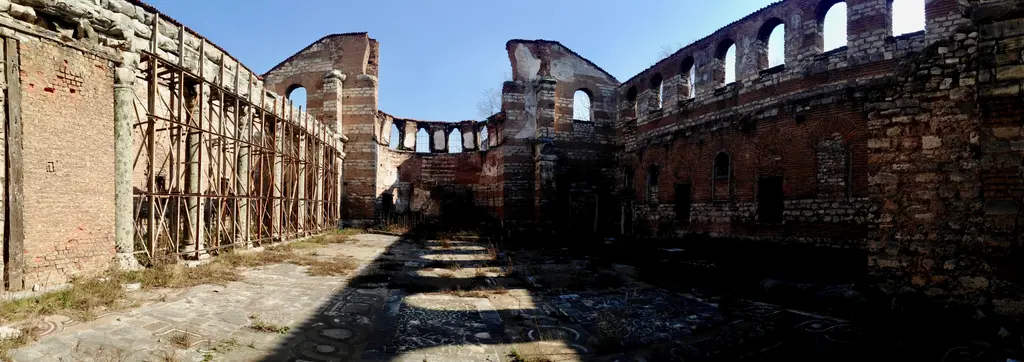 İmrahor İlyas Bey Camii'nin üstü açık iç mekânı; solda ahşap iskeleyle desteklenen sütun dizisi, iki yanda kemerli pencereli duvarlar, zeminde renkli taş kakma döşeme.