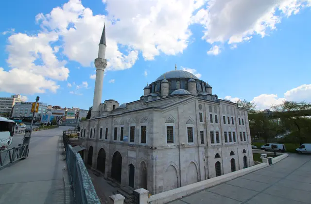 Azapkapı'da Sokullu Mehmed Paşa Camii; kesme taş gövde, kurşun kubbe, ince minare, önde köprü yolunun korkuluğu ve bulutlu mavi gökyüzü.