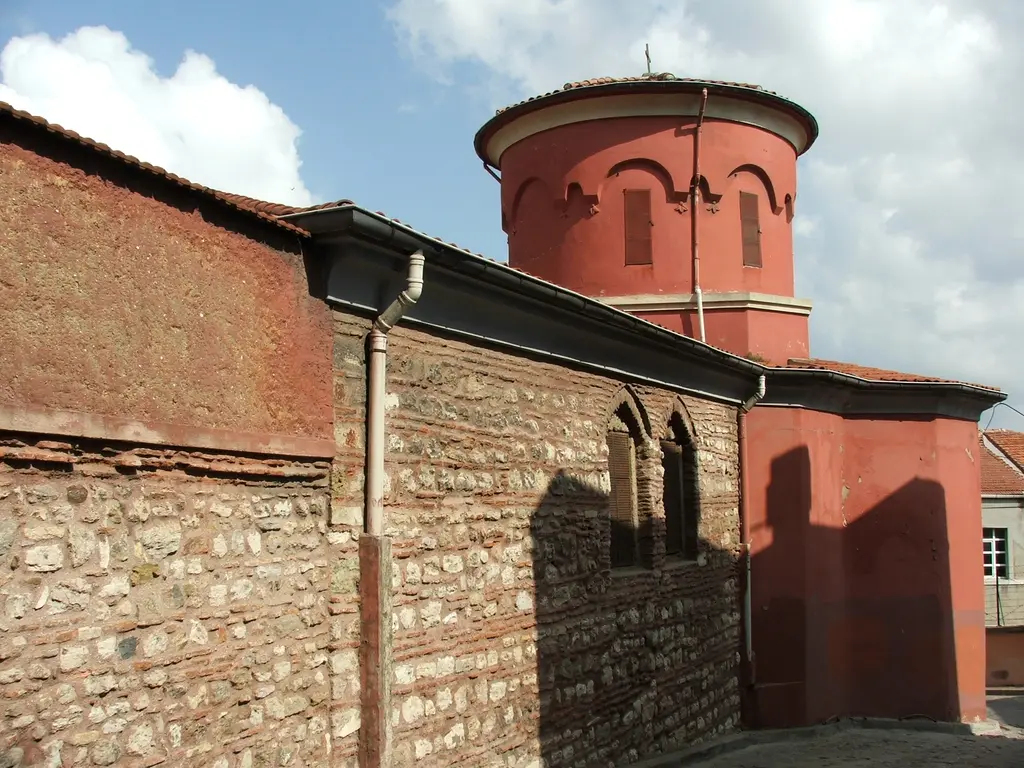 Kanlı Kilise'nin kırmızı kubbe kulesi; kemerli pencereler, altında kiremit çatı, taş ve tuğla sıralı duvar ve ikiz sivri kemerli pencere.