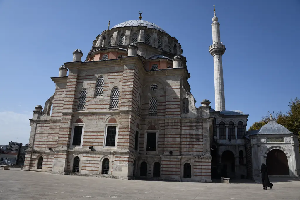 Laleli Camii'nde kubbe ve minare; kurşun kaplı ana kubbe, pencereli kasnak, yanında çokgen gövdeli minare ve açık gökyüzü.