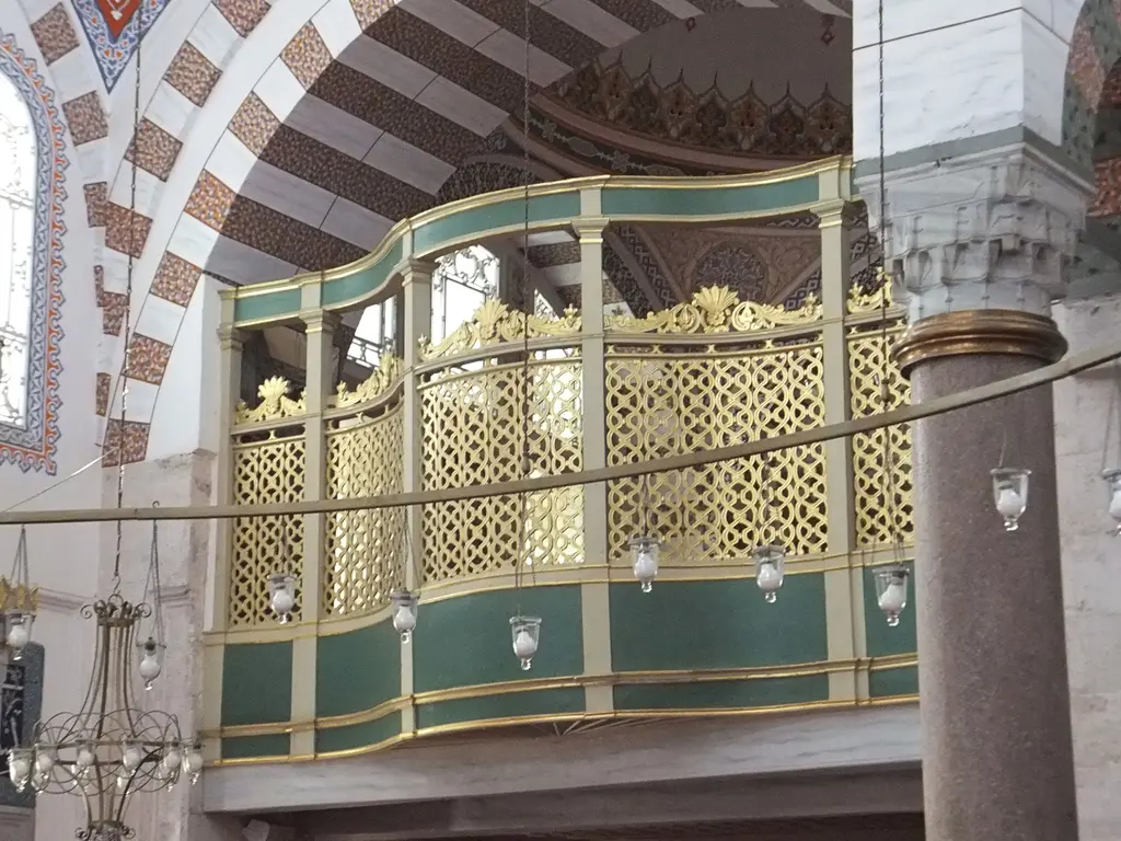 Atik Valide Camii'nde hünkâr mahfili; yeşil ve altın renkli oymalı kafesler, kemerler ve sütun.