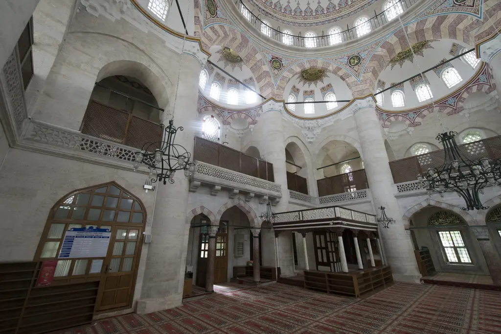 Nişancı Mehmed Paşa Camii'nin içinde ahşap müezzin mahfili, üstünde mermer şebekeli galeri, kemerli pencereler ve büyük demir avize.