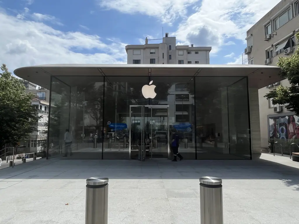 Bağdat Caddesi'nde Apple mağazası; cam cepheli tek katlı yapı, düz beyaz çatı, önünde demir direkler ve arkada apartman.