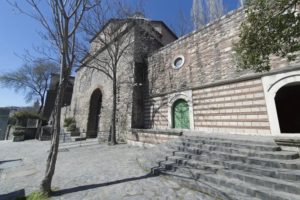 Tophane-i Âmire'nin doğu yanı; taş merdivenler, kemerli bir giriş, yeşil kapılı taş bina ve önünde bir ağaç.