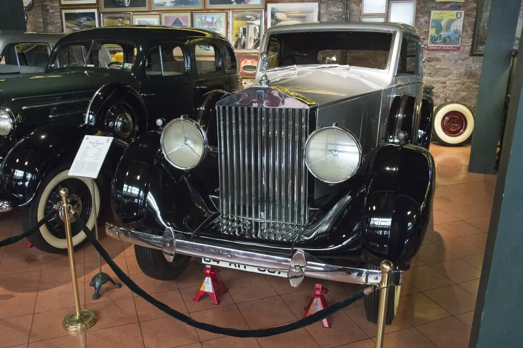 Rahmi Mustafa Koç Müzesi'nde klasik otomobiller; önde krom ızgaralı siyah gri bir Rolls-Royce, yanında siyah bir sedan ve duvarda afişler.