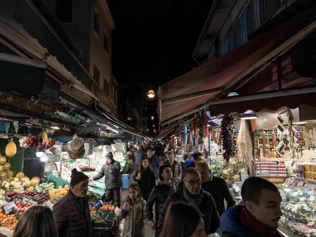 Kadıköy Çarşısı'nda akşam; tentelerin altında manav ve balıkçı tezgâhları, sokakta yoğun kalabalık.