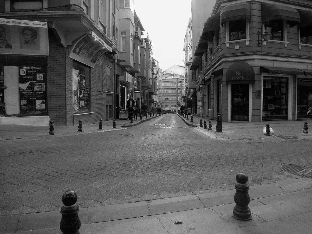Moda Caddesi'nin siyah beyaz görünüşü; köşe binası, kaldırım babaları, taş döşeli yol ve dükkân vitrinleri.