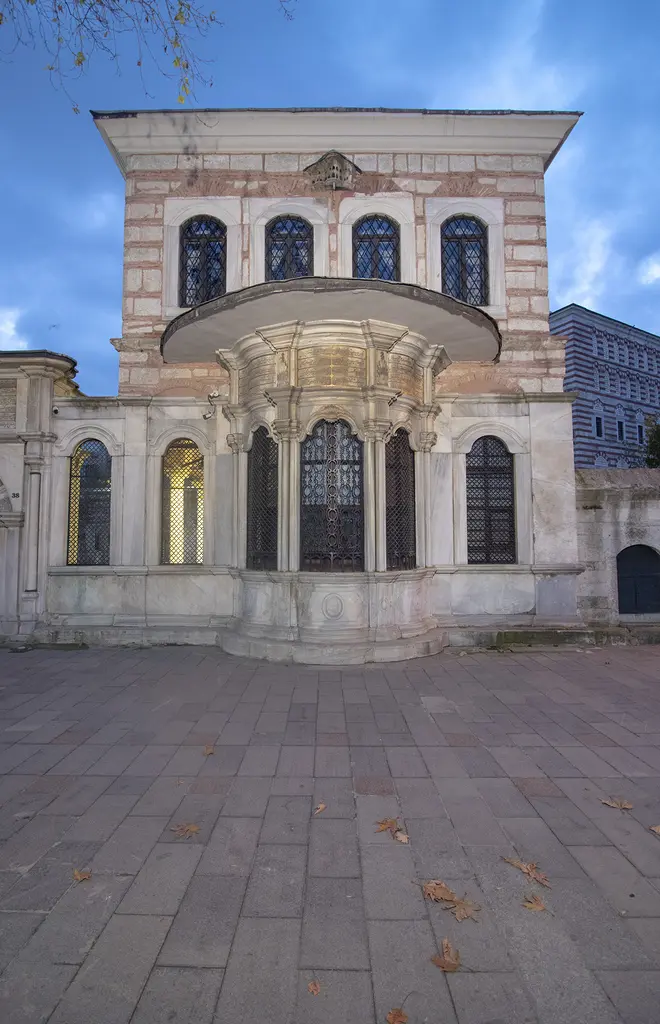 Şah Sultan Sebili ve üstündeki mektep; mermer sebil, şebekeli pencereli pembe taş kat ve önünde parke taşlı meydan.