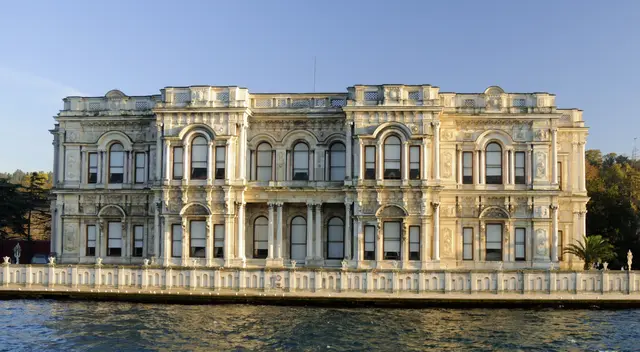 Boğaz'dan Beylerbeyi Sarayı; akşam ışığında krem rengi mermer cephe, iki kat kemerli pencereler ve önünde rıhtım.