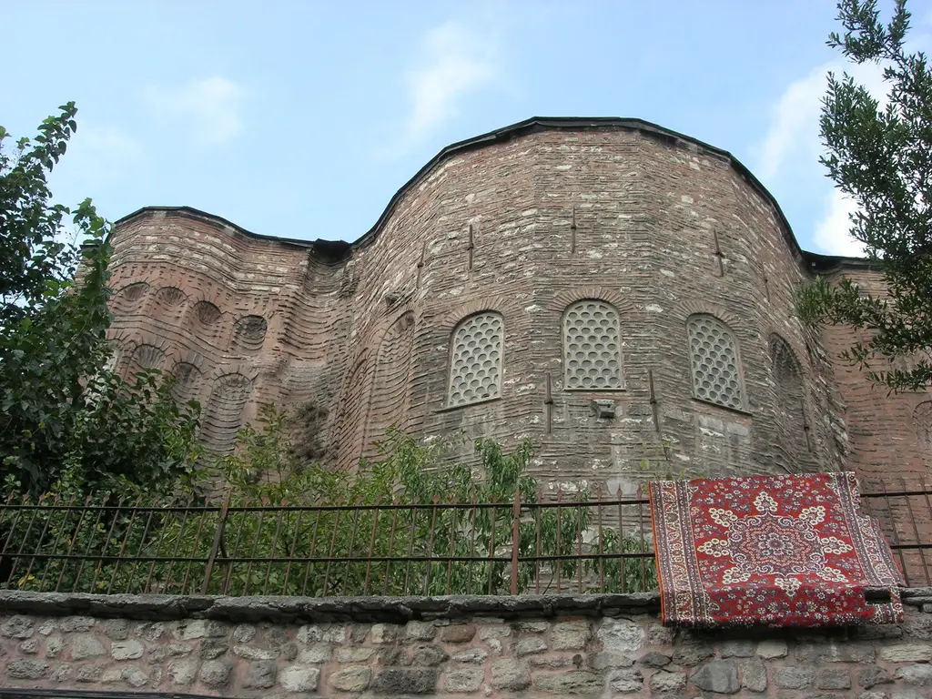 Gül Camii'nin doğu ucu; geniş ana apsiste üç petek gözlü pencere, solda kat kat nişli yan apsis ve korkuluğa havalanmaya asılmış kırmızı halı.