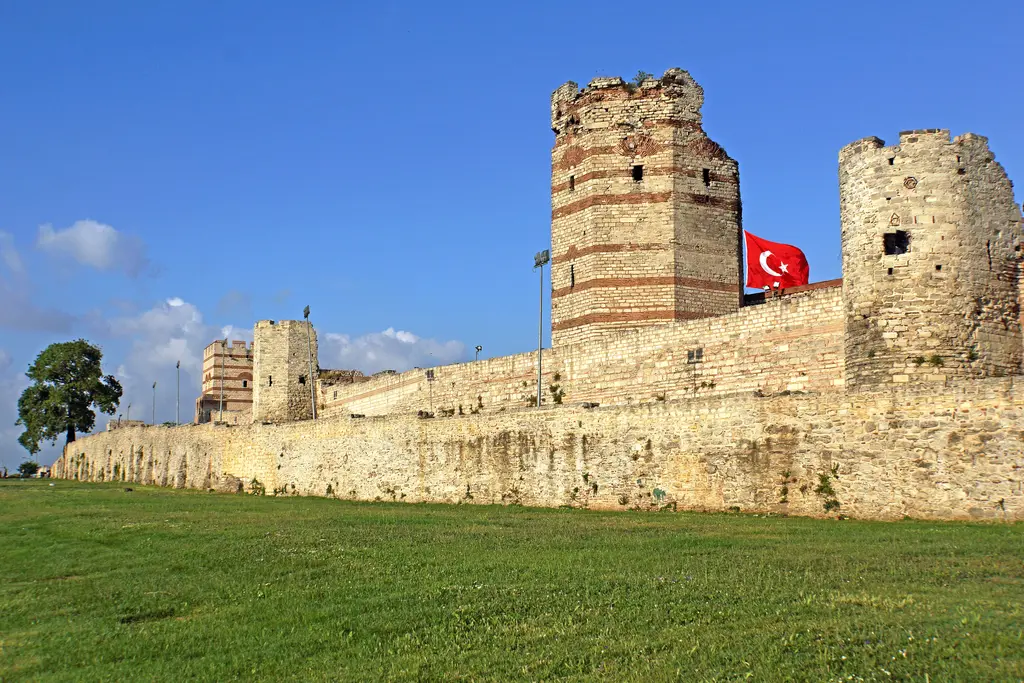 Sur hattı boyunca bakış; öndeki alçak dış sur, arkasındaki yüksek iç sur, sıralanan kuleler ve kulelerden birinde dalgalanan bayrak.