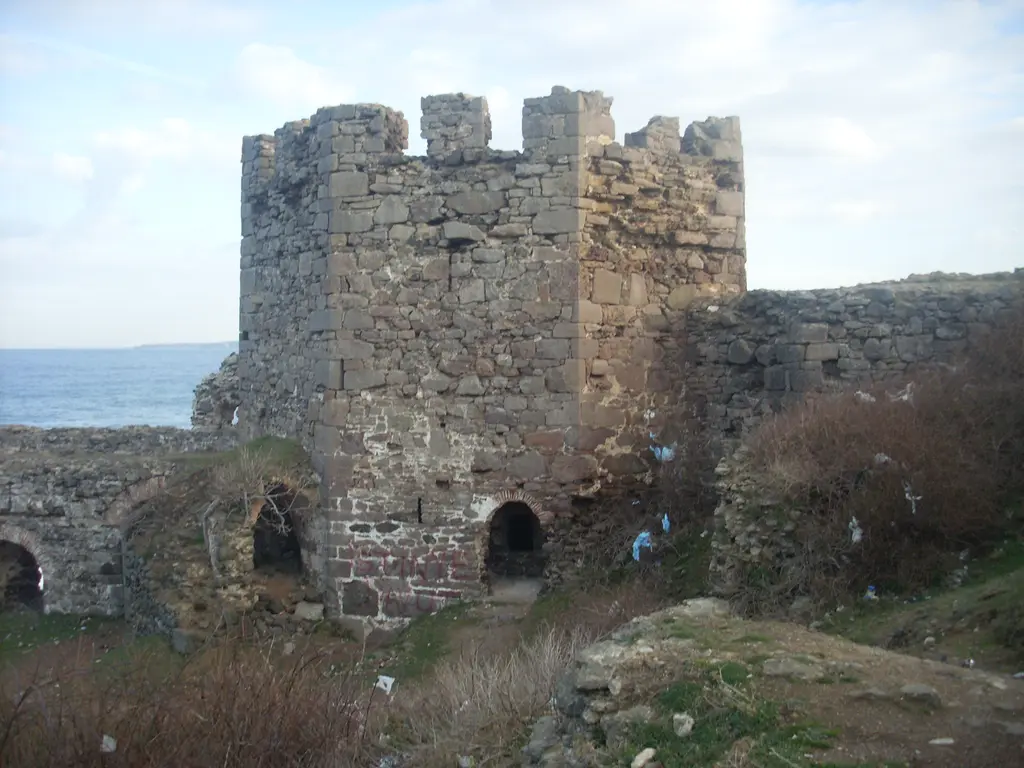 Rumeli Feneri Kalesi'nde burç; mazgallı kare kule, kemerli kapı ve yanındaki çökmüş sur duvarı.