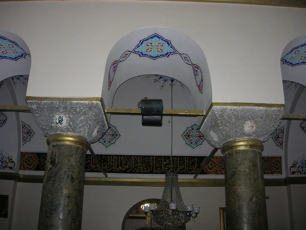 Koca Mustafa Paşa Camii'nde iki devşirme sütun; yeşilimsi gri mermer gövdeler, üstlerinde altın yaldızlı Bizans başlıkları, arkada kalem işi kemerler ile yeşil zeminli hat kuşağı.