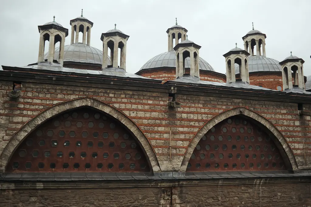 Tophane-i Âmire'nin çatısı; kurşun kaplı kubbelerin üstünde küçük fenerler, altta büyük delikli kemerler ve ağaç dalları.