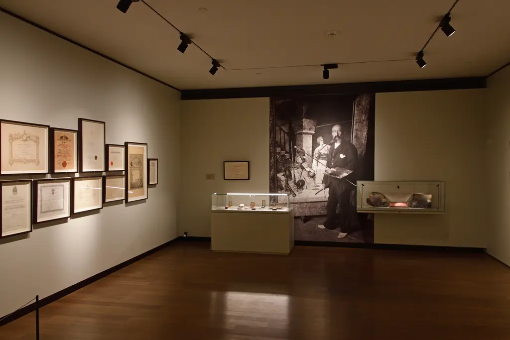 İstanbul Resim ve Heykel Müzesi'nde Osman Hamdi Bey salonu; çerçeveli belgeler, cam vitrinler ve ressamın büyük siyah beyaz fotoğrafı.