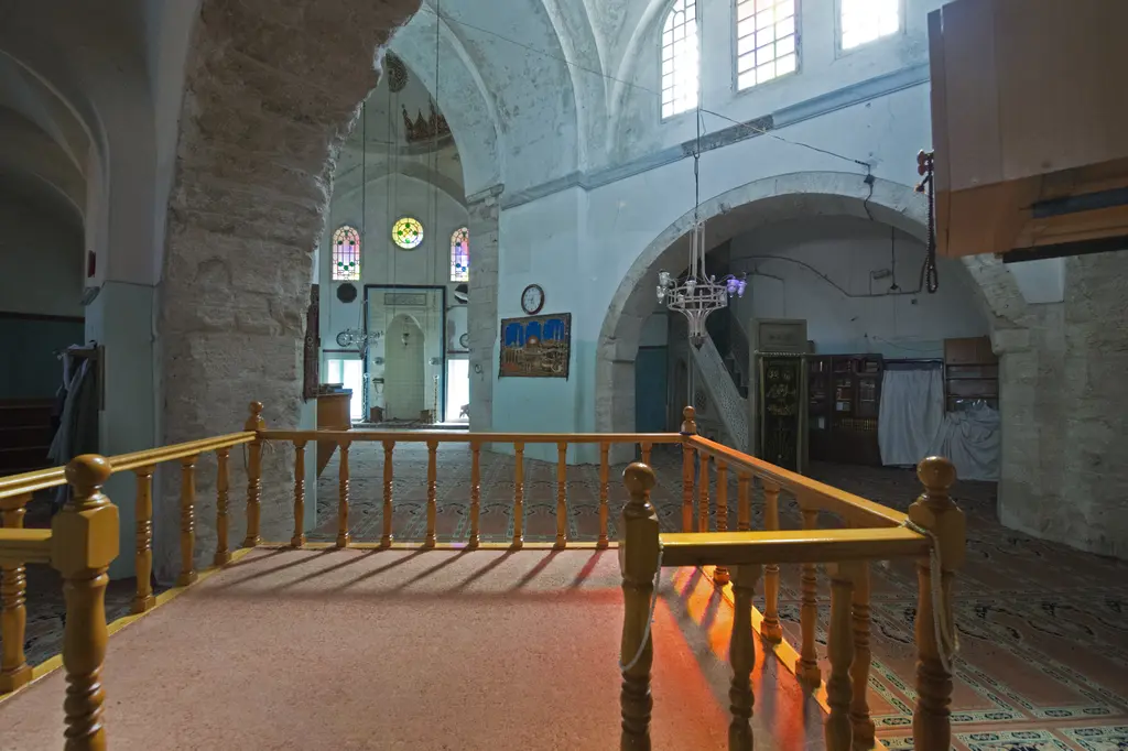 Fethiye Camii'nin cami bölümünde müezzin mahfili; ahşap korkuluklu yükseltilmiş platform, arkasında kemerli duvar ve tavandan sarkan avize.