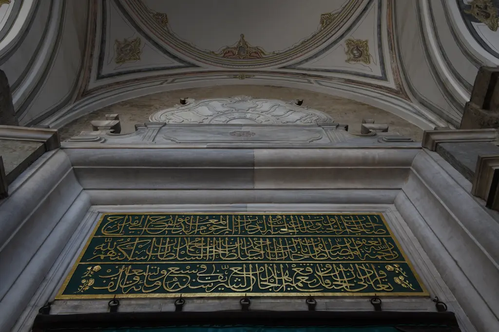 Laleli Camii'nde harim kapısı; kapının üstünde yeşil zeminli altın yaldızlı kitabe, çevresinde kıvrımlı barok mermer çerçeve.