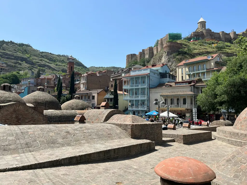 Tiflis'te Abanotubani mahallesinin tuğladan yapılmış alçak kubbeli kükürt hamamları; arkada eski şehir ve kayalık yamaç.