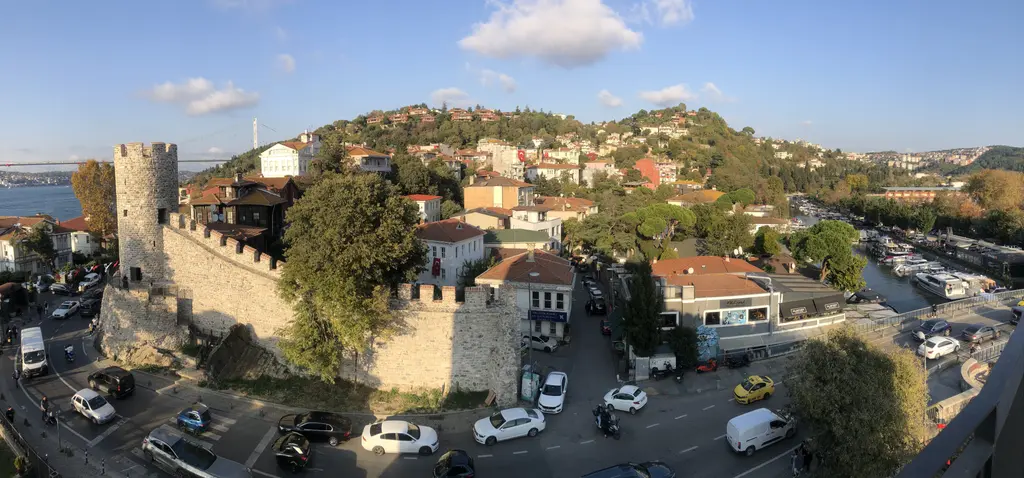 Anadolu Hisarı panoraması; mazgallı dış sur, yuvarlak kule, yamaçtaki evler ve sağda Göksu kıyısı.