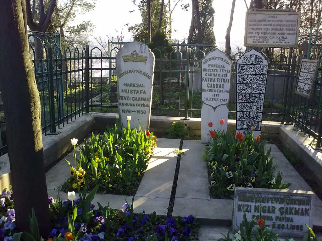 Eyüp Mezarlığı'nda Mareşal Fevzi Çakmak'ın kabri; demir parmaklıklı açık türbe, beyaz mezar taşları, laleler ve çiçekler.