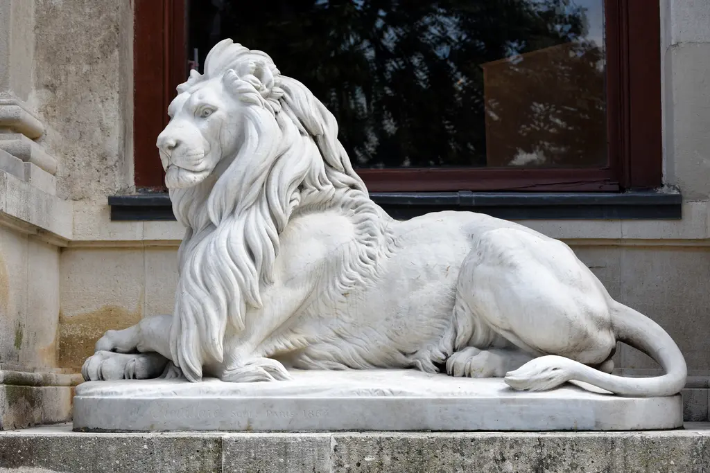 Beylerbeyi Sarayı'nda mermer aslan heykeli; kaide üzerinde yatan yeleli aslan, arkada sarayın pencere pervazı.