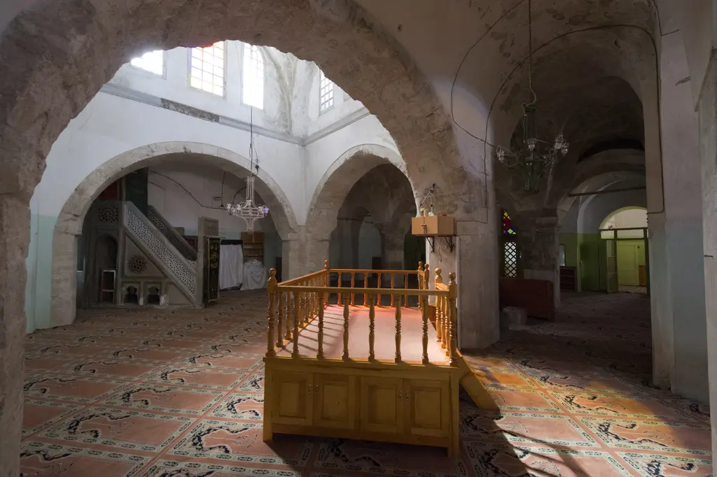 Fethiye Camii'nin cami bölümü; geniş kemerler, beyaz sıvalı duvarlar, ahşap korkuluklu mahfil merdiveni ve zeminde desenli halı.