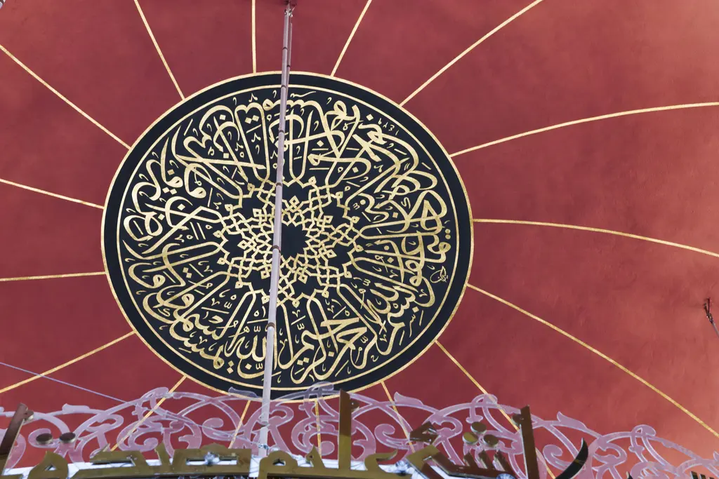 Şakirin Camii'nde kubbe göbeği; kırmızı zeminde siyah çerçeveli büyük madalyon, içinde altın renkli istif hat.