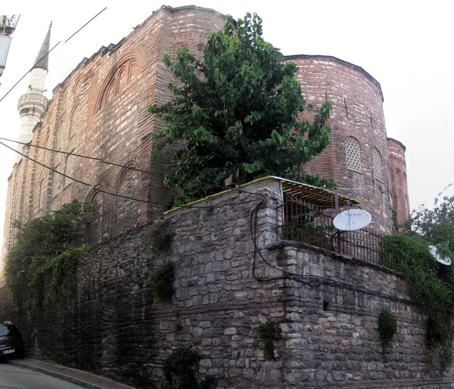 Fatih'te Gül Camii'nin güneydoğu köşesi; taş istinat duvarının üstünde yükselen tuğla ve taş örgülü gövde, sağda dışa taşkın apsisler, solda minare.