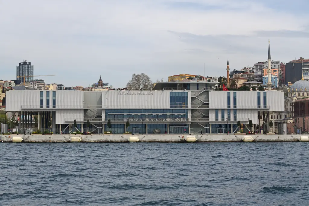 Denizden İstanbul Modern'in yeni binası; Boğaz kıyısında gri cepheli yapı, arkasında Beyoğlu yamacı ve minareler.