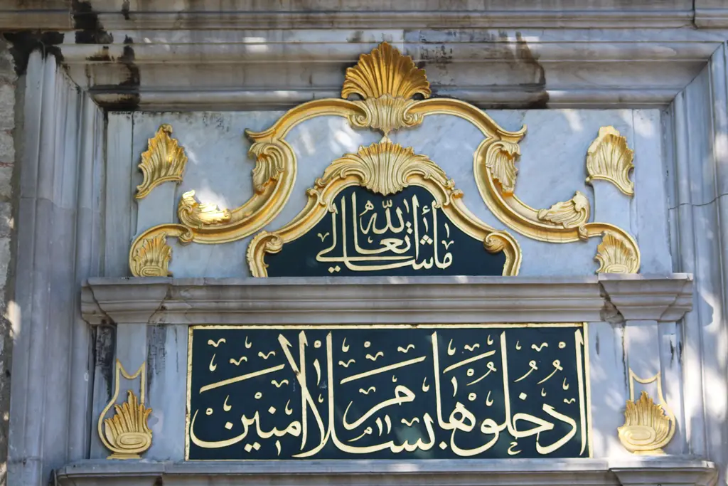 Eyüp Sultan Camii'nde kapı kitabesi; yaldızlı barok çerçeve içinde iki satır altın renkli Arapça yazı.
