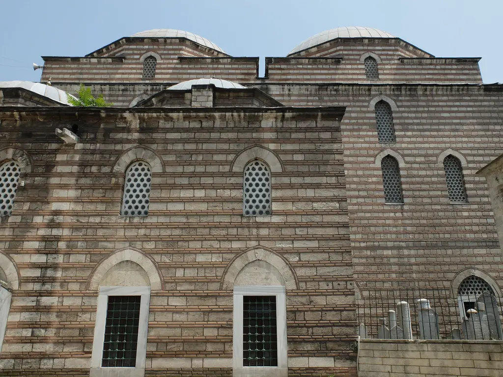 Murat Paşa Camii'nin yan cephesi; taş ve tuğla sıralarıyla örülmüş duvar, kemerli pencereler ve üstte tabhane kubbeleri.