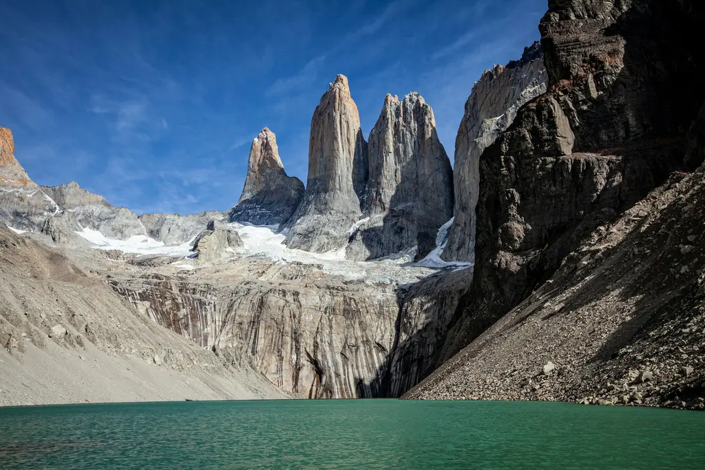 Şili'de Torres del Paine; gökyüzüne uzanan granit kuleler, önündeki turkuaz göl ve bozkır.