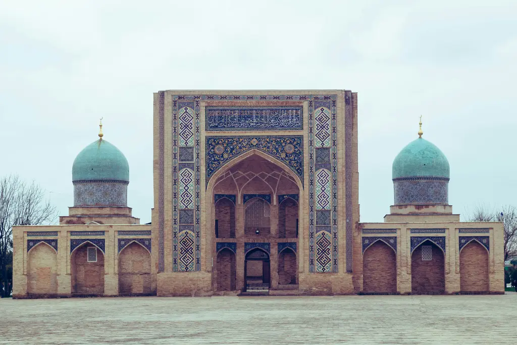 Taşkent'te Hazrati İmam Kompleksi'nin çifte mavi kubbeli camisi ve iki minaresi; önünde geniş taş avlu.