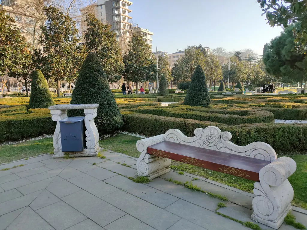 Göztepe Parkı'nın barok bahçesi; kıvrımlı beyaz taş bank, budanmış koni biçimli ağaçlar ve şimşir desenleri.