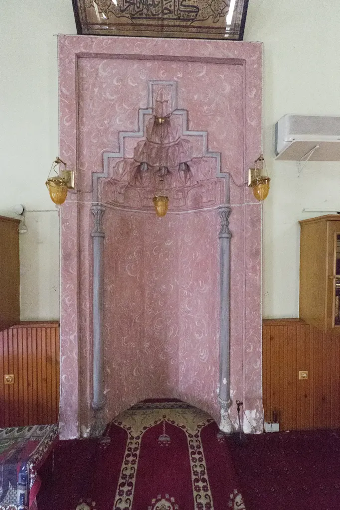 Defterdar Camii'nin mihrabı; mukarnas kavsaralı pembe mermer niş, üstünde levha, yanlarda pencereler ve kırmızı halı.