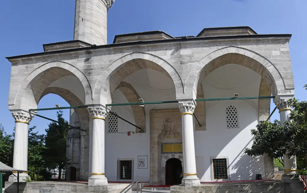 Firuz Ağa Camii'nin son cemaat revakı karşıdan; üç sivri kemer, beyaz mermer sütunlar, ortada mukarnaslı kapı nişi ve yanlarda pencereler.